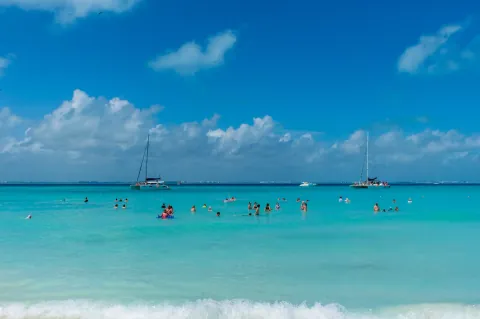 Swimmers and sailboats in the turquoise waters of Isla Mujeres
